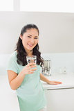 Portrait of a woman with a glass of water in kitchen