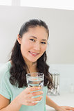 Close-up of a woman with a glass of water in kitchen