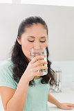 Close-up of a young woman drinking water in kitchen