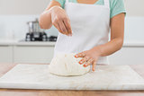 Mid section of a woman kneading dough in kitchen