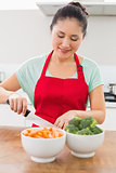 Smiling woman chopping vegetables in kitchen