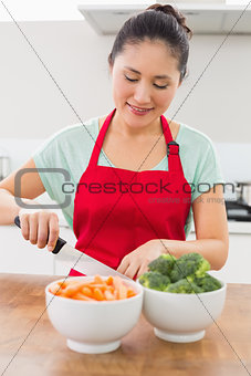 Smiling woman chopping vegetables in kitchen