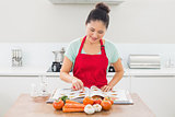 Woman with recipe book and vegetables in kitchen