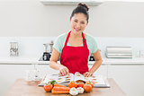 Smiling woman with recipe book and vegetables in kitchen