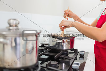 Mid section of a woman preparing food in kitchen