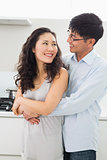 Man embracing woman from behind in kitchen