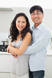 Young man embracing woman from behind in kitchen