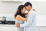 Side view of a man embracing woman in kitchen