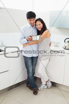 Full length of a woman embracing man in kitchen