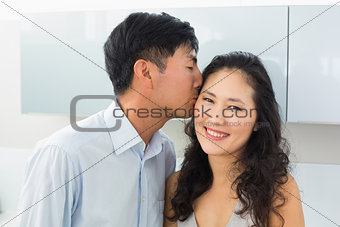 Close-up of a young man kissing woman in kitchen