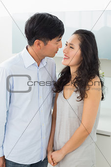 Side view of a romantic young couple in kitchen