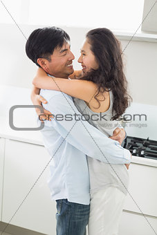 Side view of a young man embracing woman in kitchen