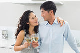 Loving young couple with wine glasses in kitchen