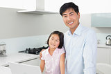 Smiling father and young daughter with laptop in kitchen