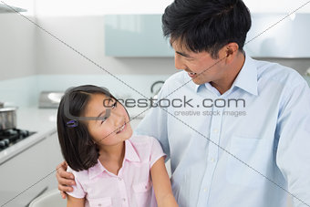 Smiling father and young daughter in kitchen