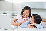 Two smiling young girls with laptop in kitchen