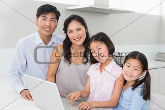 Portrait of a family of four with laptop in kitchen