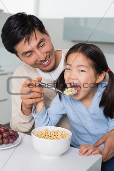 Father with young daughter having cereals in kitchen