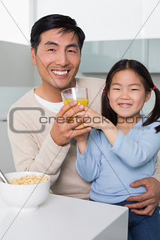 Happy father with daughter having breakfast in kitchen