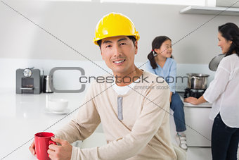 Man in hard hat with family in background at home