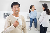 Smiling man holding coffee cup with family in background