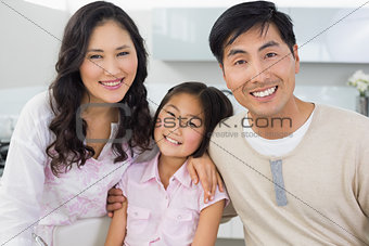 Portrait of a smiling couple with a daughter in kitchen