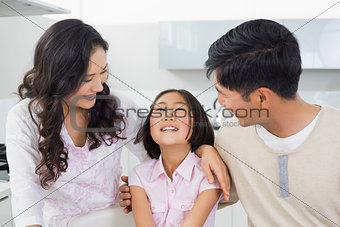 Smiling couple with a cheerful daughter in kitchen