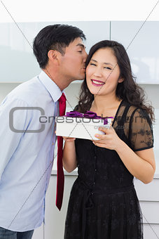 Young man kissing a woman as he gives her a gift box