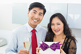 Portrait of a happy young couple with a gift box and champagne