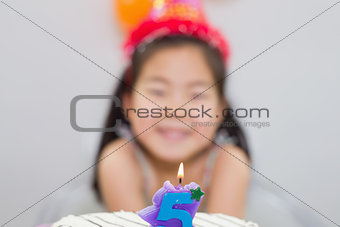 Blurred little girl with lit candle on birthday cake