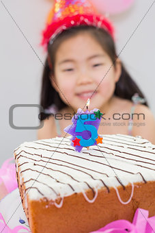Blurred little girl with lit candle on birthday cake