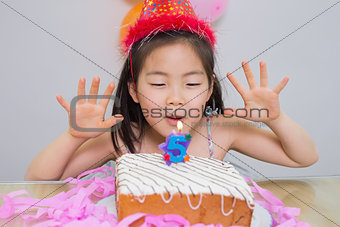 Cute little girl blowing her birthday cake
