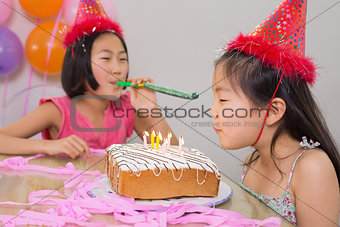 Girls blowing noisemaker and birthday candles