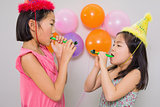 Girls blowing noisemakers at a birthday party