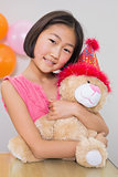 Cute little girl hugging soft toy at a birthday party