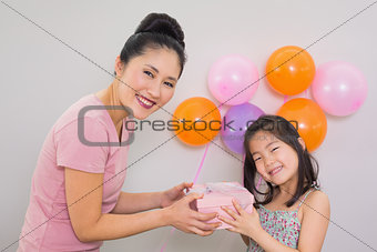 Woman giving gift box to a little girl at a birthday party