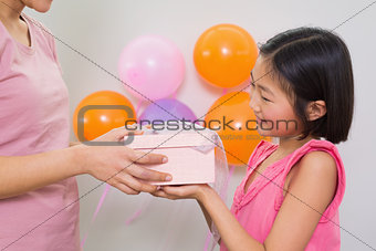 Woman giving gift box to a little girl at a birthday party
