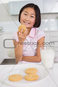 Smiling young girl enjoying cookies and milk