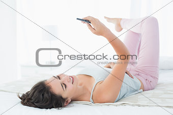Relaxed woman looking at mobile phone in bed