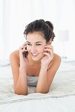 Beautiful smiling woman using mobile phone in bed