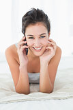 Beautiful smiling woman using mobile phone in bed
