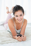 Relaxed young woman with mobile phone in bed