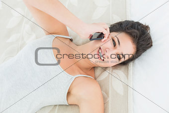 Close-up of a happy woman using mobile phone in bed