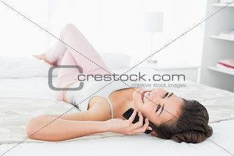 Relaxed young woman using mobile phone in bed