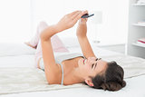 Relaxed woman with mobile phone lying in bed
