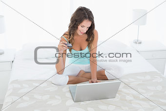 Casual young woman doing online shopping in bed