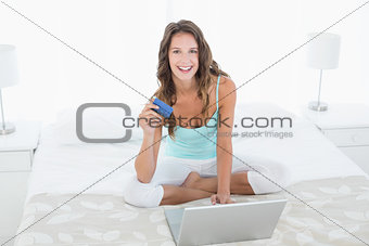 Portrait of a woman doing online shopping in bed