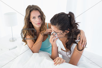 Woman consoling a crying female friend in bed