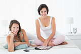 Relaxed smiling female friends with magazine in bed