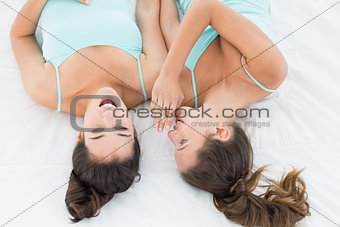 Two young female friends gossiping in bed